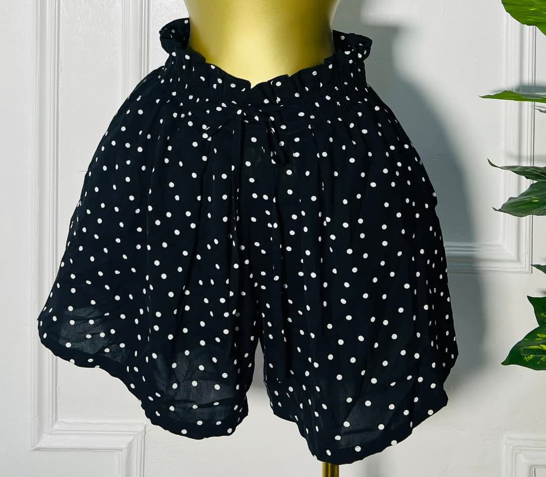 Front view of DotChic™ black high-waisted polka dot shorts with ruffled waistband and tie front, size 12"